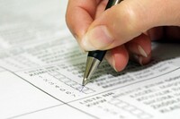 Dłoń, która trzyma długopis i zaznacza krzyżykiem pole w formularzu.
