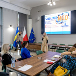 Pani p.o. Zastępcy Dyrektora Biura Spraw Społecznych Monika Siemion wita uczestników szkolenia dla NGO w sali z ekranem, na którym wyświetlony jest tytuł wydarzenia, oraz flagami województwa śląskiego, Polski i Unii Europejskiej