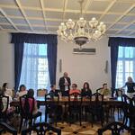 Mężczyzna stoi za uczestnikami warsztatów którzy siedzą przy stołach.